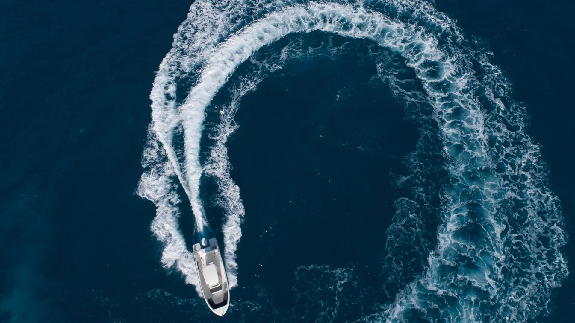 Motorboot zieht einen Bogen aus Gischt – Luftaufnahme