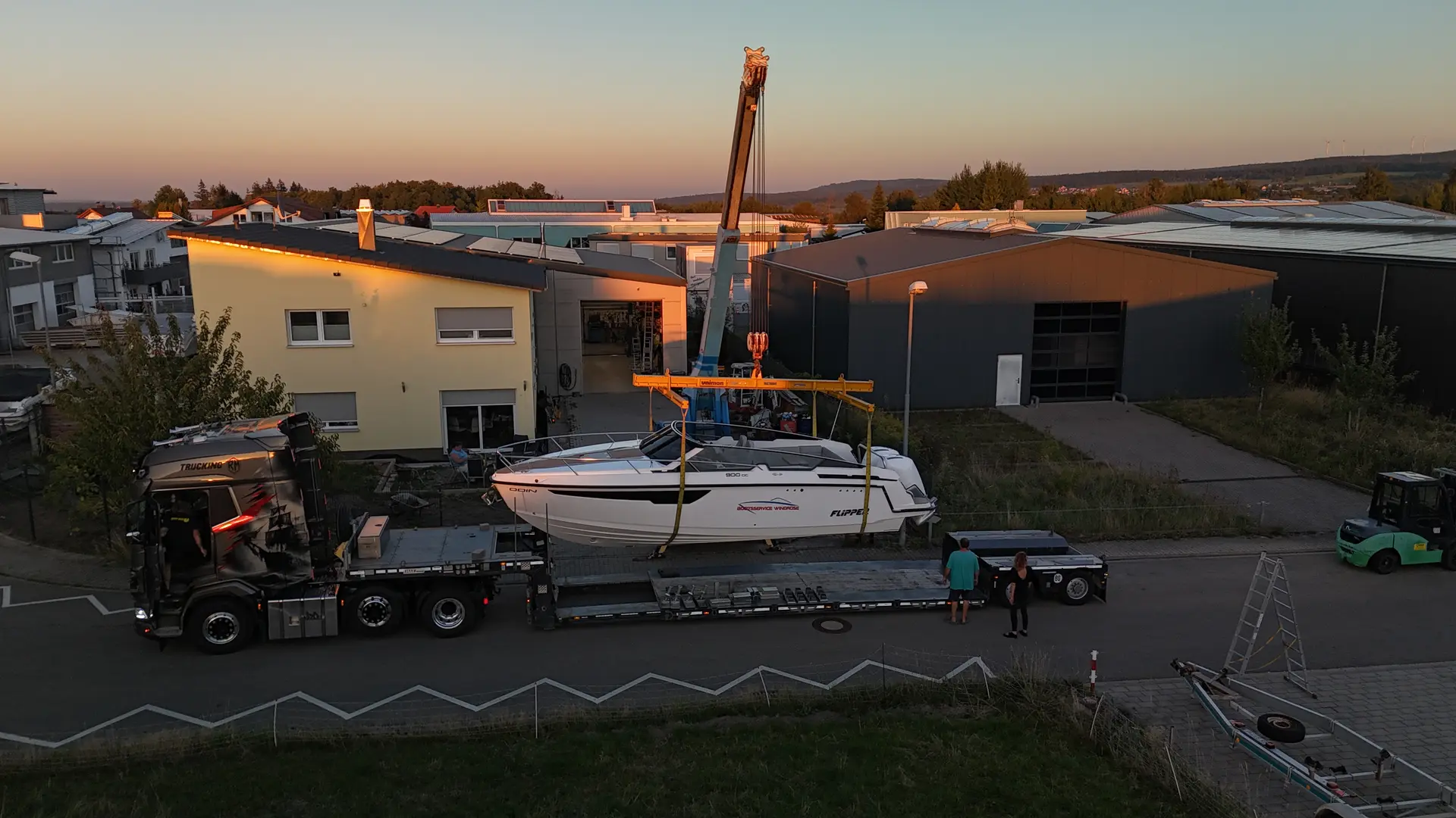 Motorboot wird in der Abenddämmerung mit dem Kran verladen